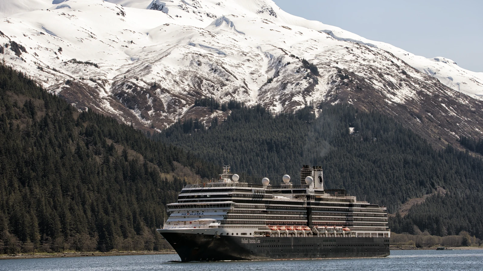 Eurodam Holland America cruise ship sailing near a wooded coastline